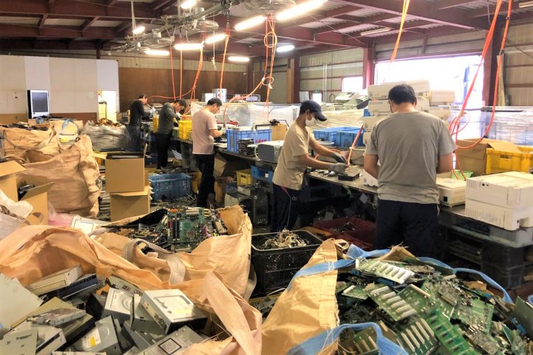 国際商事のリサイクル専用工場で、作業員が届いた機器を手作業で分解する現場